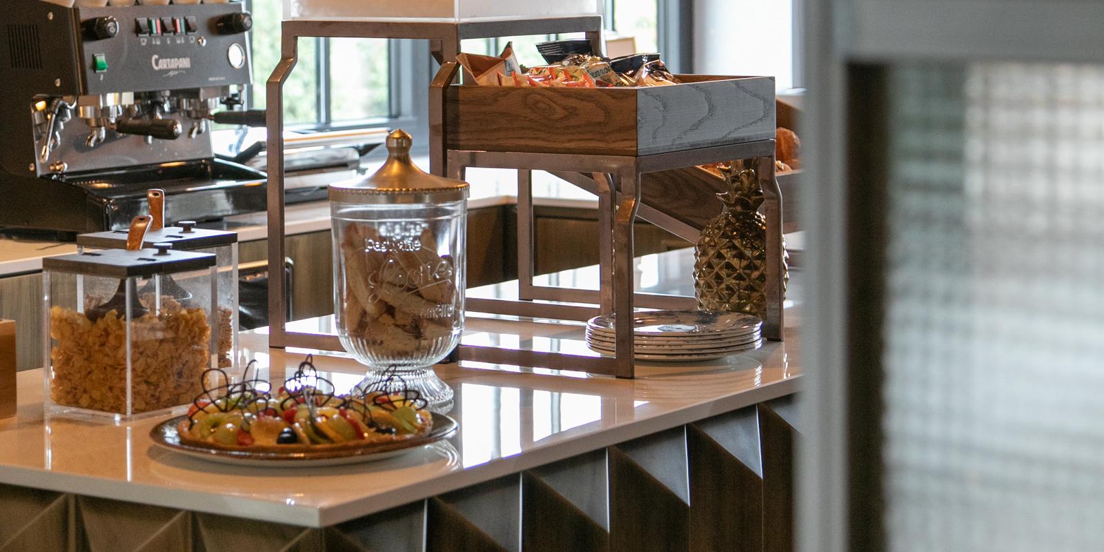 Buffet with coffee machine, cereals, pastries, and decorative pineapple.