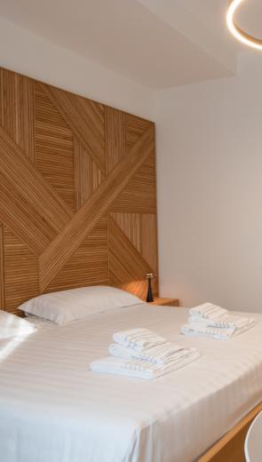 Camera moderna con letto matrimoniale, TV, scrivania e decorazione geometrica in legno.