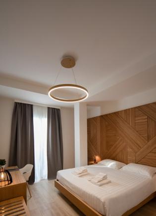 Modern bedroom with wooden accents, circular light fixture, and cozy ambiance.