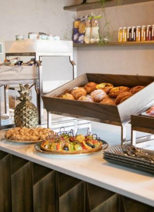 A breakfast buffet with pastries, fruits, and various condiments on display.