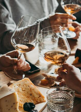 Friends toasting with wine glasses over a table with cheese platters.