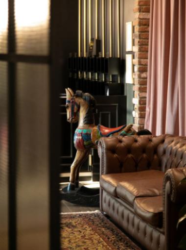 Vintage room with leather sofa, brick wall, and colorful carousel horse.