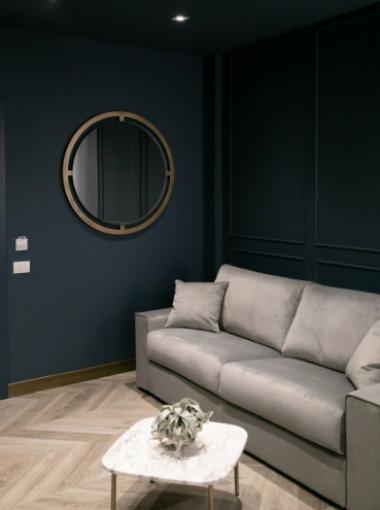 Modern living room with gray sofa, round mirror, and marble coffee table.