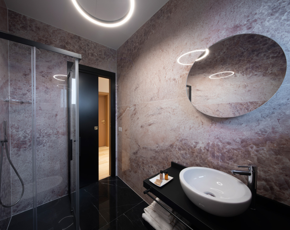 Modern bathroom with round mirror, glass shower, and stylish sink.