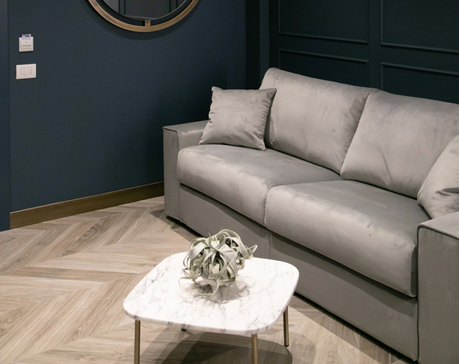 Modern living room with gray sofa, round mirror, and marble coffee table.