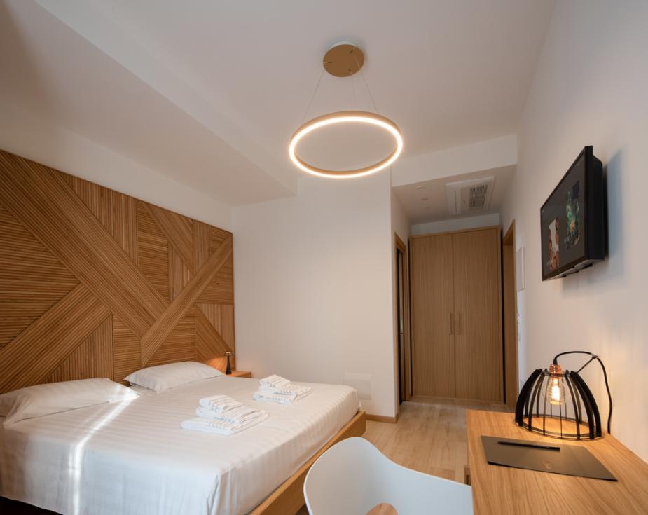 Modern bedroom with a stylish wooden headboard, circular light fixture, and a desk.