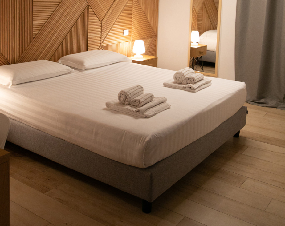 Modern room with double bed, elegant lighting, and wooden decorations.