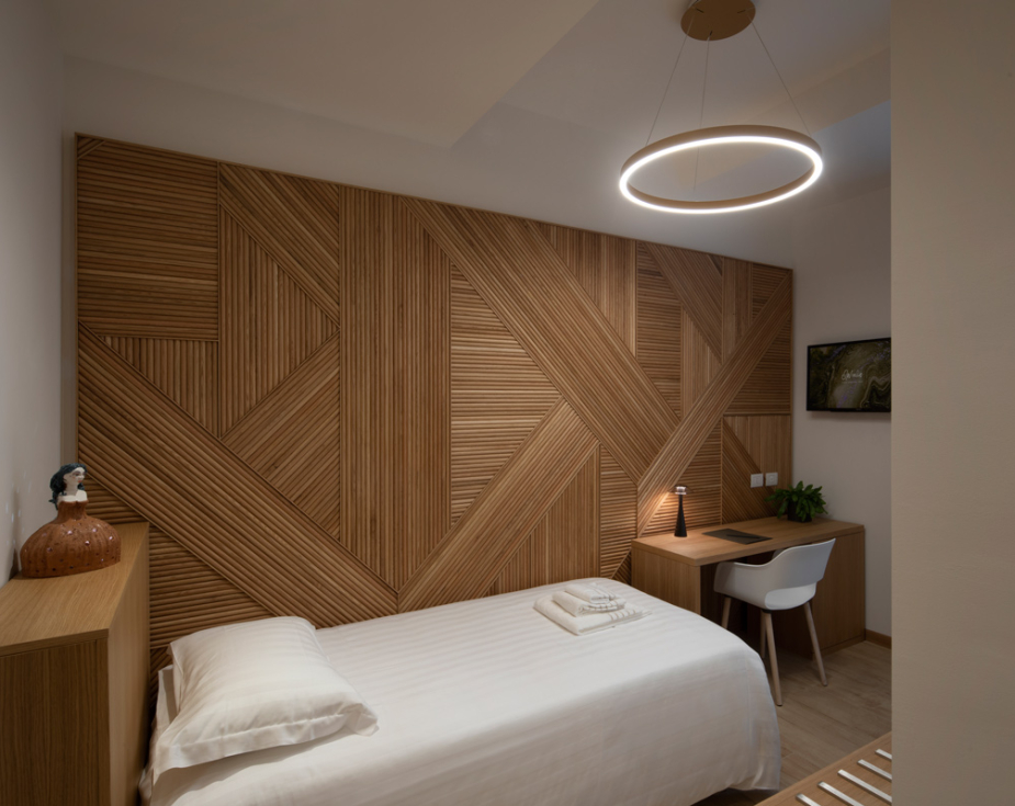 Modern bedroom with wooden accents, single bed, desk, and adjacent bathroom.