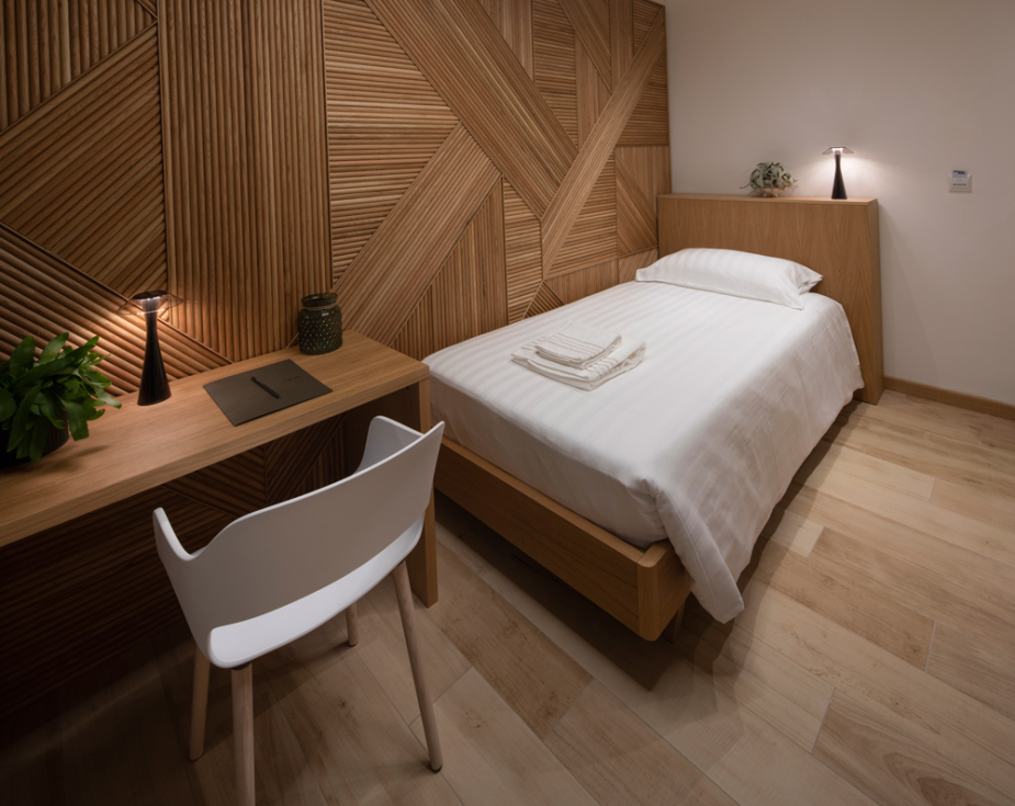 Modern room with single bed, wooden walls, and circular lighting.