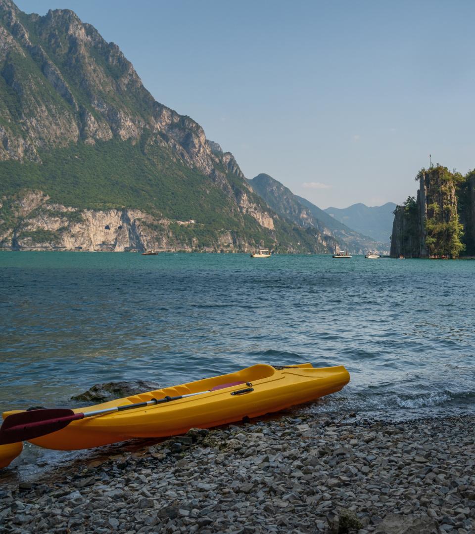 Yellow kayak on rocky shore, with mountains and lake in the background.